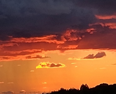 Ciemne chmury rozświetlone czerwonym blaskiem tworzą dramatyczny krajobraz nad wodą. Fotografia pokazuje niezwykłą grę światła podczas wieczoru w Jastarni.